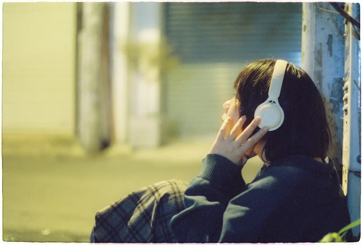 女性がヘッドホンを通して夜の都市環境で音楽を聴いている