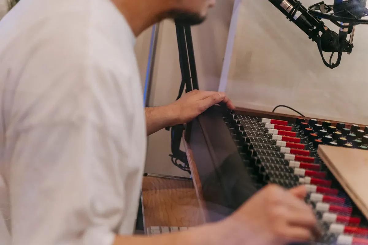 Close-up of a musician working on an audio mixer in a professional music studio.
