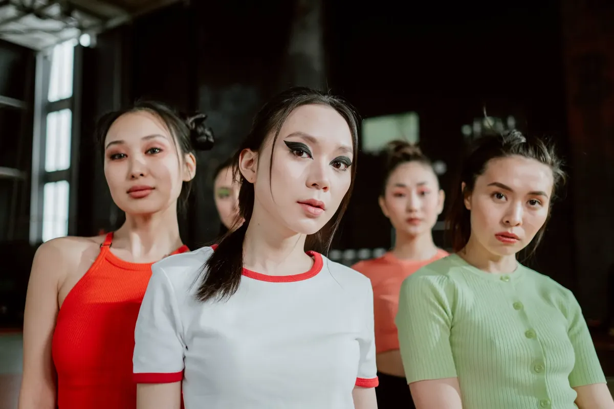 A group of stylish young women poses confidently indoors, showcasing diverse fashion styles and makeup.