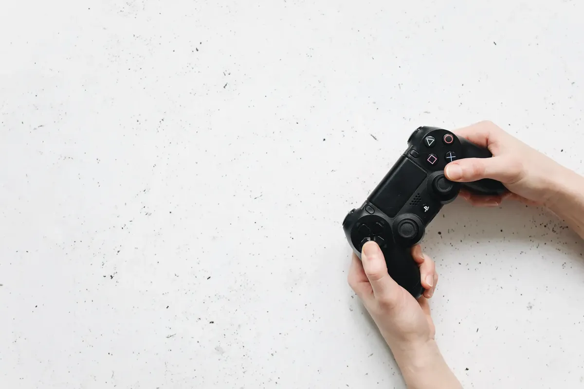 Close-up of hands holding a black game controller on a white background.